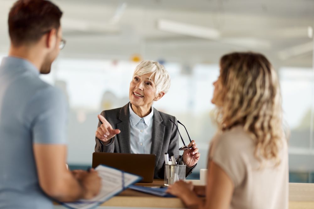 Ältere Dame diskutiert in einem Büro mit zwei jüngeren Personen